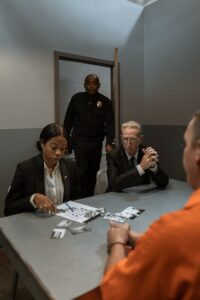 Une scène d'interrogatoire policier tendue avec des officiers et un prisonnier dans une salle de prison.