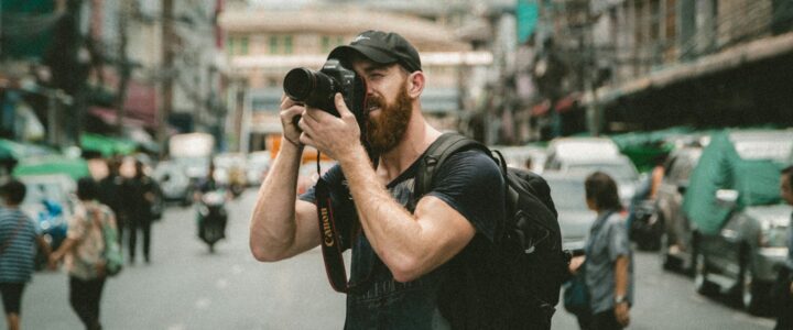 shallow focus photography of man using a DSLR camera