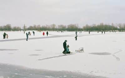 People ice skating and sledding on a frozen lake.