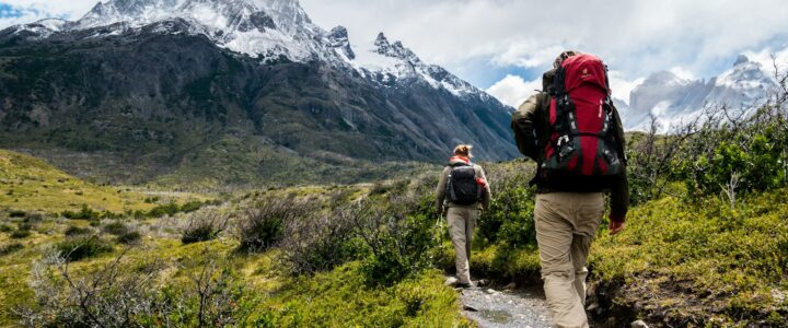 two person walking towards mountain covered with snow