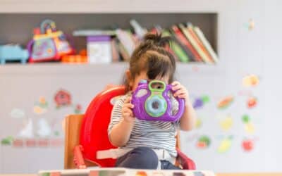 girl holding purple and green camera toy