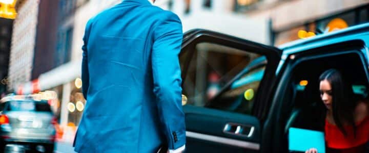 man wearing blue suit standing beside vehicle