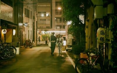 Couple in traditional attire walks a narrow street at night.