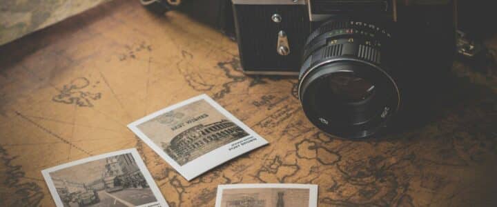 black and grey DSLR camera near several photos on brown map