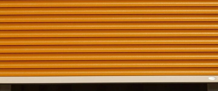 Volet roulant orange fermé sur fenêtre, cadre blanc en bas